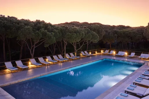 Outdoor pool surrounded by white pool chairs