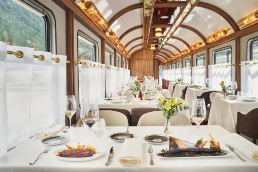 Dining area within a train, with tables and plates of food on top