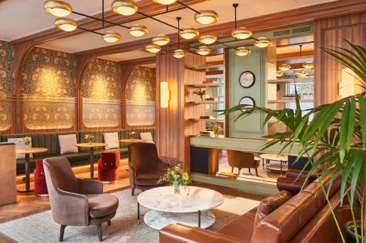 Lounge with wooden walls and cushioned sofas and chairs around circular tables