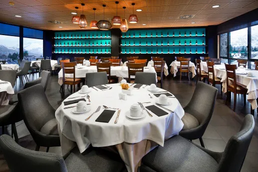 Indoor bar and dining area with black and wooden chairs, with bottles of alcohol along the wall