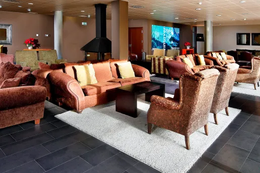 Lounge with red and brown, cushioned chairs with a metal fireplace in the center