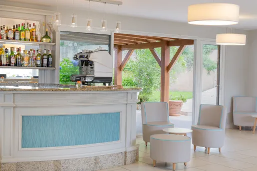Bar with liquor on the wall and circular tables and chairs to the right
