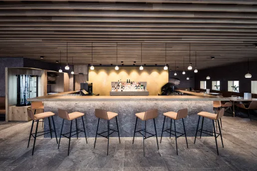 Bar in the center of a lounge, surrounded by wooden stools