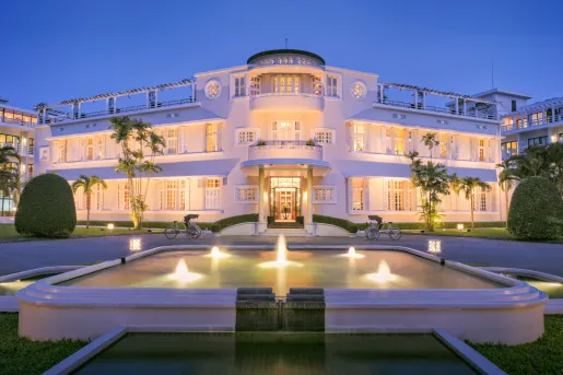 Exterior view of illuminated white building with an illuminated fountain in front