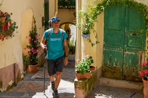 Man with a walking pole going through alleyways of a town