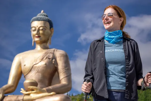 Woman walking in front of a giant temple with a Buddhist statue in the background