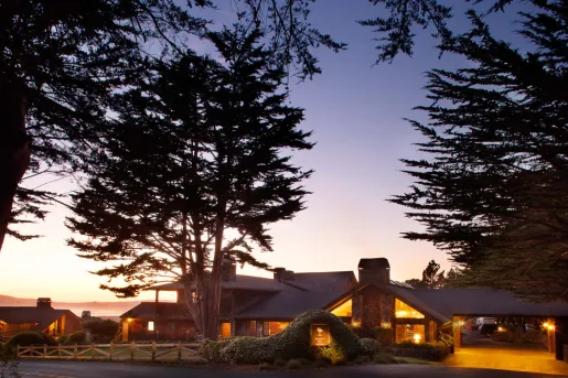 Outdoor view of a hotel entrance, illuminated by orange lights and the sunset