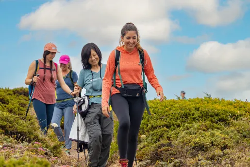Group of four women descending a dirt trail, surrounded by bushes