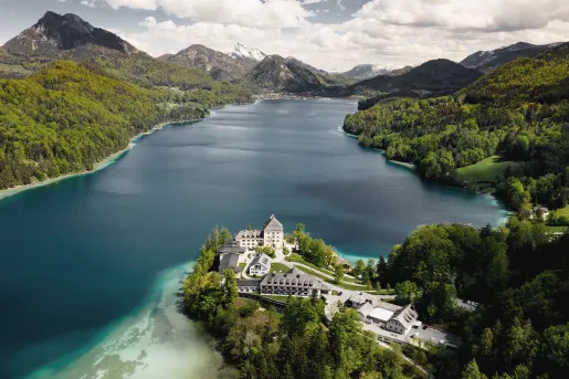 Large blue lake surrounded by mountains with hotel on its shore