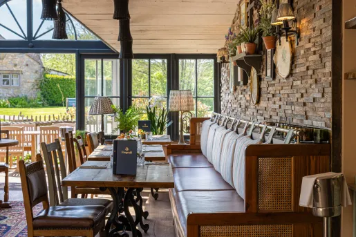 Restaurant dining hall with cushioned sofas and chairs surrounding square dining tables