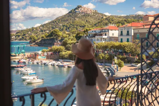 Woman standing on a balcony, looking out towards the ocean