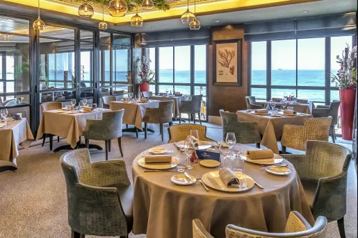 Restaurant with circular tables and large windows with views of the ocean
