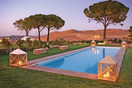 Outdoor pool, surrounded by tall trees and hills in the distance