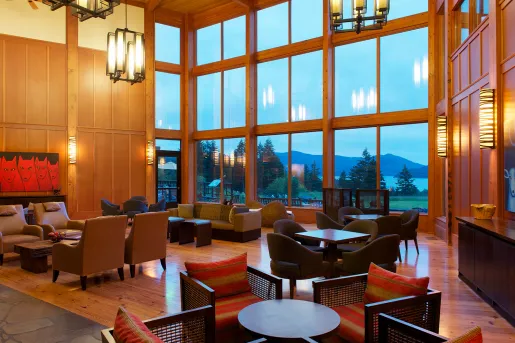 Lounge and seating area with cushioned chairs and tables, with a large glass wall
