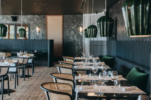 Indoor dining hall with woven chairs and green sofas