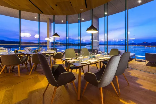 Dining area with large windows, looking out to a lake in the distance