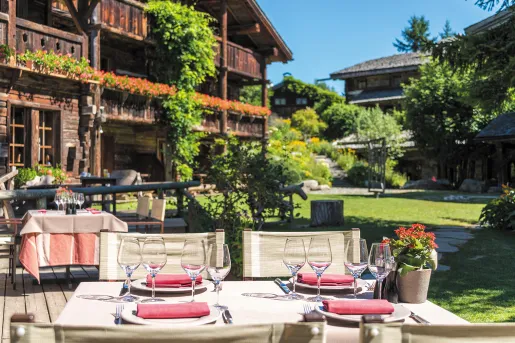 Dining table outdoors with two wooden lodges in the background