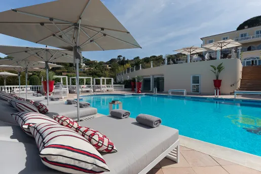Outdoor pool surrounded by gray reclining chairs and white umbrellas