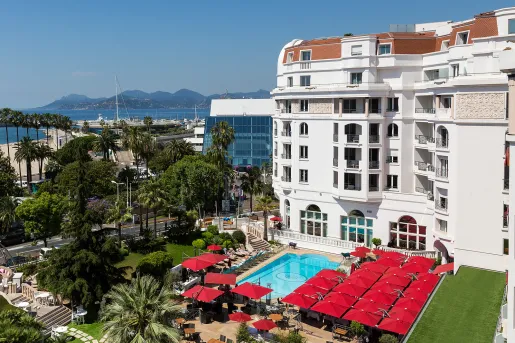 Exterior view of multi-story hotel building with an outdoor pool looking out to the ocean