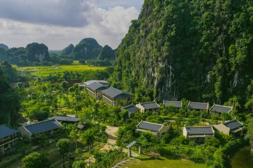 Multiple white buildings surrounded by thick forest and tall mountains