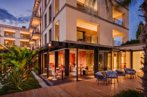 Exterior, nighttime view of hotel buildings with cushioned chairs