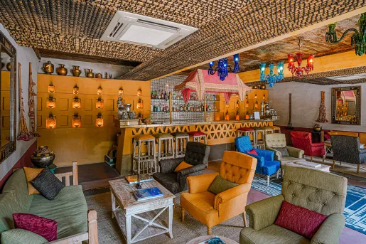 Indoor bar and lounge with cushioned sofas and colorful light fixtures
