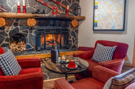 Lounge with cushioned red chairs in front of a stone fireplace