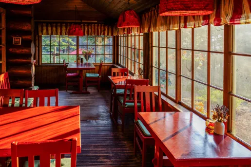Cabin restaurant with red tables and chairs, with large windows along the walls