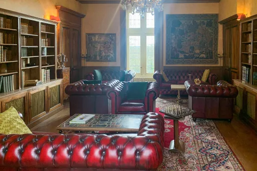 Library room with red leather couches and paintings on the walls