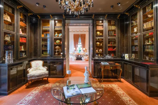 Library with large, wooden and marble shelves and cushioned chairs