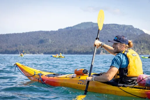 Man smiling, wearing a lifejacket while paddling in a kayak