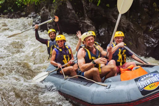 Group of people smiling and paddling in a raft in a river