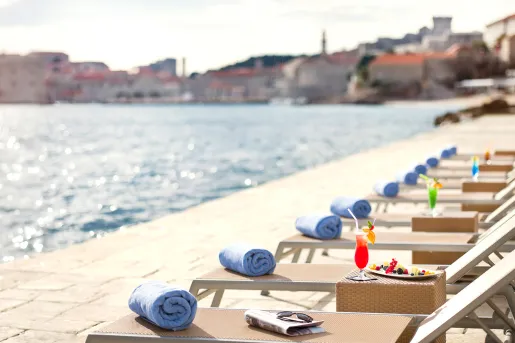 Row of reclining pool chairs on a dock in front of the ocean