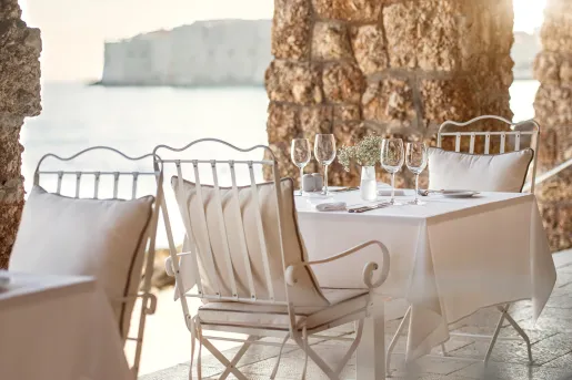 Outdoor patio with large stone pillars and white dining tables with wine glasses