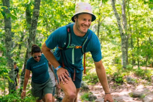 Man and woman smiling while ascending through a forest