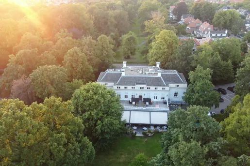 Exterior, sky view of white building surrounded by tall trees