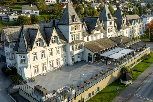 Exterior sky view of white and gray hotel building with a stone patio outdoors