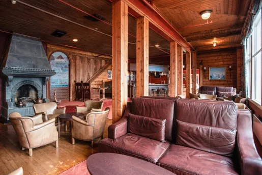 Cabin room with wooden pillars and leather couches
