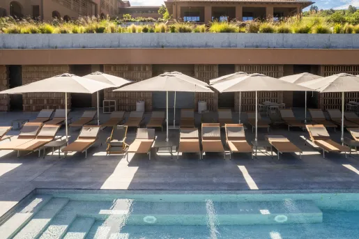 Outdoor pool with reclining, beige chairs surrounding
