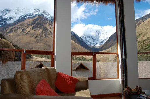 Corner room with large windows and a cushioned chair, looking out towards tall mountains
