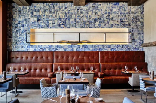 Restaurant dining hall with large, leather sofas and wine glasses on each table