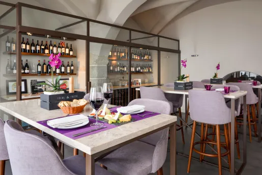 Restaurant dining hall with purple chairs and a clear shelf with bottles on wine