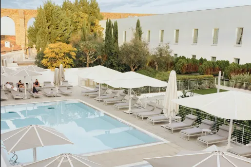 Outdoor pool surrounded by gray reclining chairs and white umbrellas