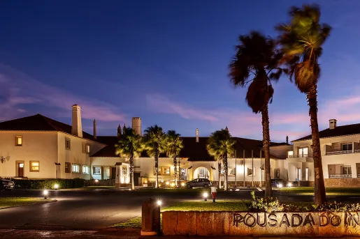 Outdoor view of white hotel building illuminated with the sunset in the background