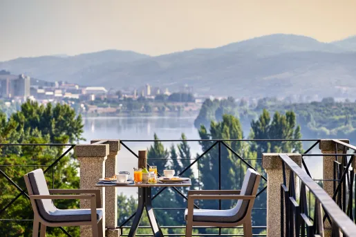 Rooftop patio with a dining tale and chairs, looking out towards a large lake