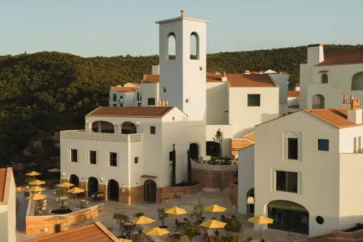 Exterior view of white hotel buildings with yellow umbrellas on the ground floor