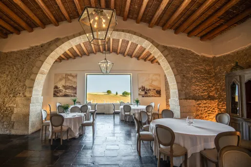 Indoor dining hall with circular tables and stone walls