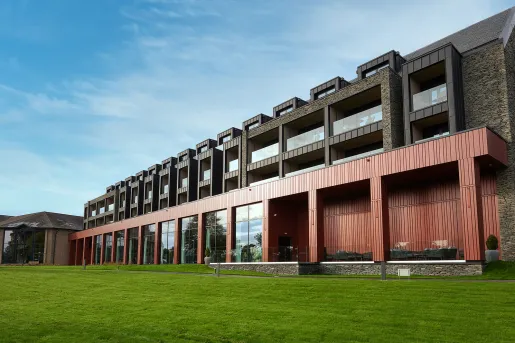 Exterior view of a long red and black building, with a grass field in front