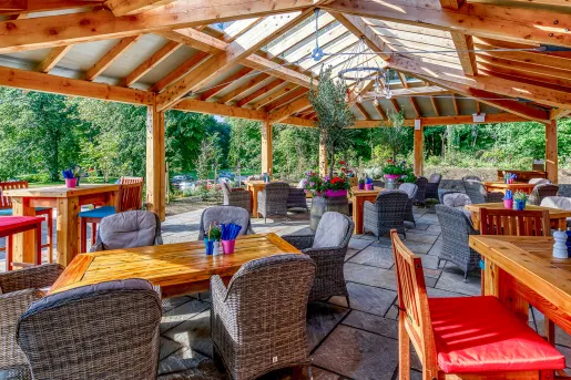 Outdoor patio and garden with cushioned, gray chairs around wooden tables