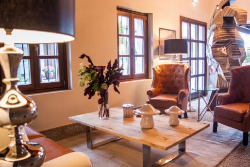 Seating area with leather couches in front of a small, wooden table with plants on top